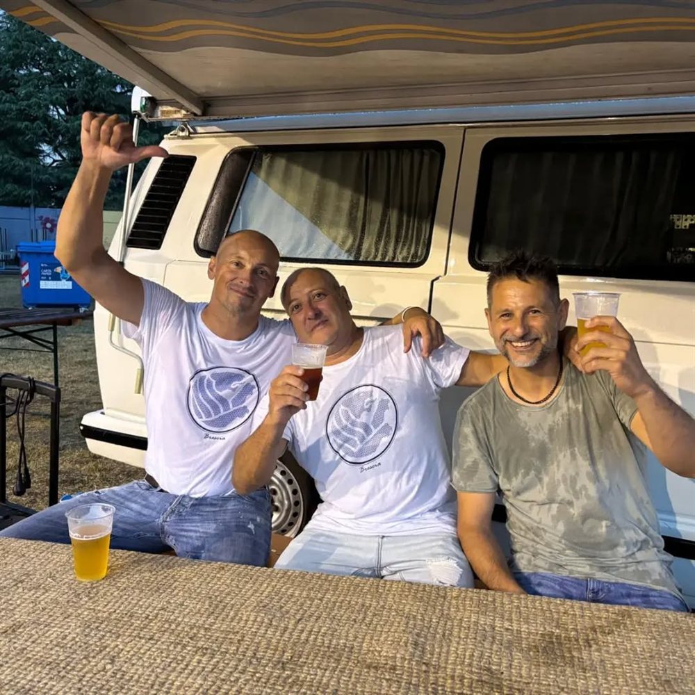 I tre musicisti dietro le quinte, seduti sul portellone di un furgone, con un bicchiere in mano