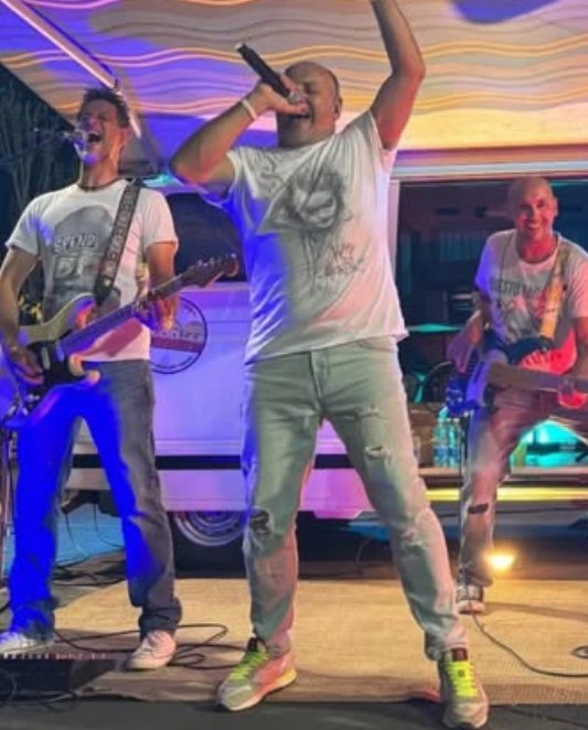 Il cantante col pugno alzato e il microfono vicino al chitarrista, durante un concerto