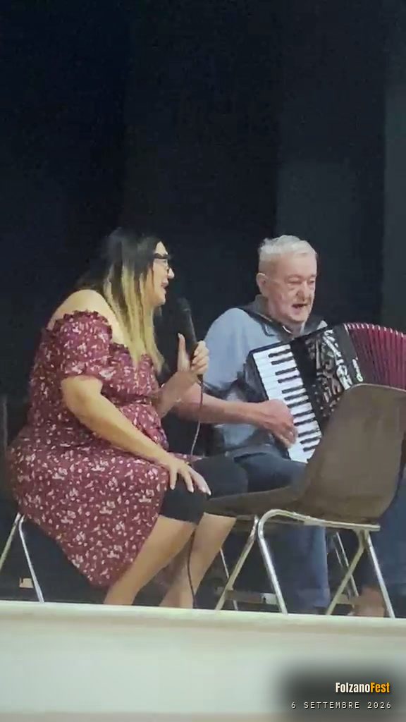 Stefania Martin canta al microfono, accompagnata dalla fisarmonica