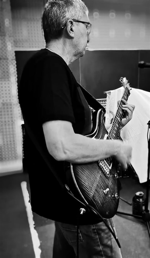 Il chitarrista del gruppo, di profilo, mentre suona in sala prove